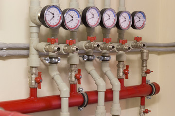 A number of identical manometers stand on plastic pipes with red valves