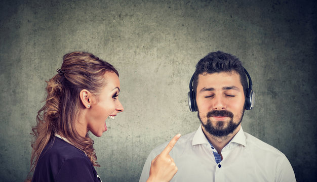 Angry woman yelling at a calm husband listening to music