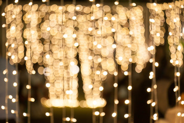  Blurry background of many little light bulb decorations in night party.