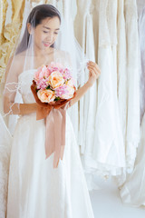 Obraz na płótnie Canvas Beautiful asian bride woman holding a bouquet on hand for wedding with feeling shy,Romantic and sweet moment