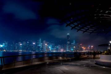 Fototapeta na wymiar Hong Kong cityscape at night. Tourists walking on the waterfront