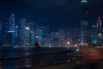 Hong Kong cityscape at night. Tourists walking on the waterfront