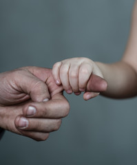 Old man and young girl holding hands together on dark background