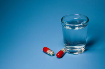 pills and glass of water on white background