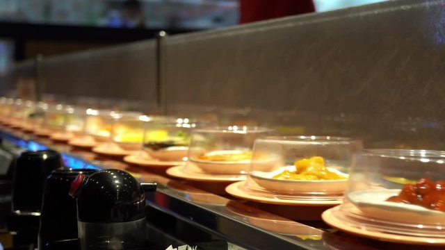 Food dishes and desserts rolling on conveyor belt restaurant