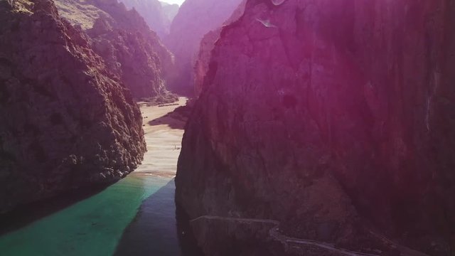 a forward flying drone shot from the from of the iconic rock gap and gorge in the distance and purple sun flare at the torrent de pareis near Port de Sa Calobra in Majorca