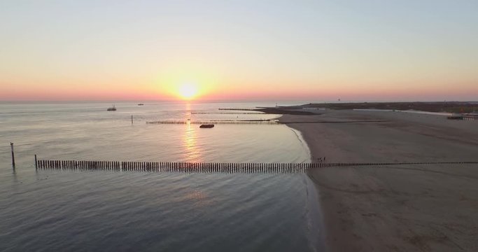 Aerial: The pier, beach and lighthouse during sunset near the village Westkapelle, the Netherlands.
