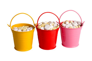 Multi-colored buckets with medical pills on a white background