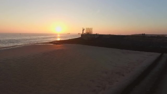 Aerial: The boulevard, beach and city of Vlissingen during sunset.