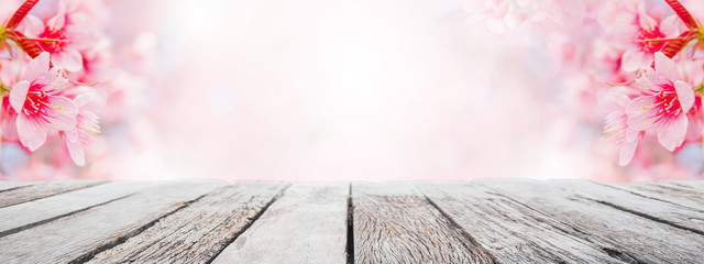 Empty wood table top and blurred sakura flower tree in garden banner background with vintage filter...