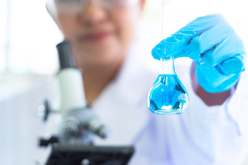 Female scientist hold and showing laboratory test tubes and solution with stethoscope. Science and Medical background. Scientist research and analysis biotechnology concept. Selective focus blue flask