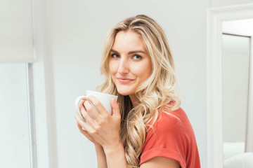 Blonde drinking coffee, tea or soup from a white cup