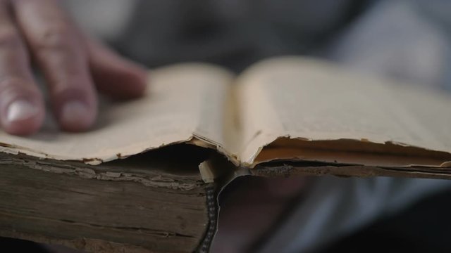 Hand and old book. A man's hand holds a book and read.  The hands are turning the pages of a very old book