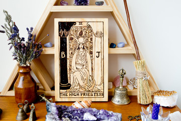 Tarot High Priestess on wooden altar space with crystals, and herbs