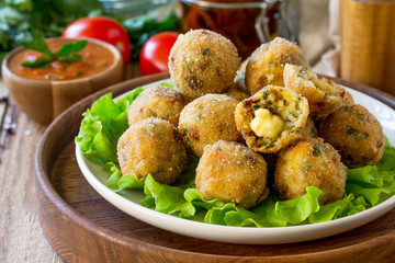 Arancini. Italian Rice Balls with Mozzarella and Sun-dried tomatoes, with tomato sauce on wooden table.