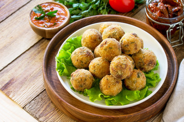 Arancini. Italian Rice Balls with Mozzarella and Sun-dried tomatoes, with tomato sauce on wooden table. Copy space.