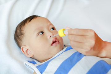 Mother dripping nasal drops for her son. Baby healthcare concept.