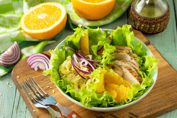 Diet menu. Healthy salad with chicken, egg pancakes, orange, green salad and dressing vinaigrette on wooden table.
