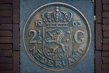 Impression of Dutch two-and-a-half guilder coin embedded as decoration in pavement. Monument to the currency from before the Euro was introduced in 2002.
