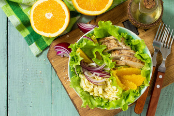 Diet menu. Healthy salad with chicken, egg pancakes, orange, green salad and dressing vinaigrette on wooden table. Top view flat lay background. Copy space.
