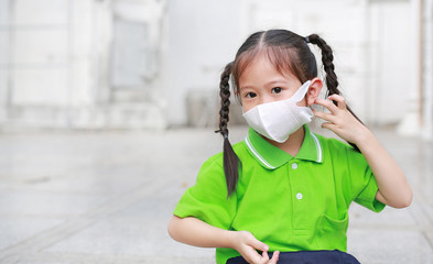 Asian child girl wearing a protection mask while outside to against PM 2.5 air pollution with...