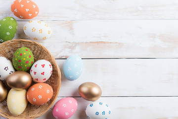 Happy easter! Colourful of Easter eggs in nest with pink tulip flower and Feather on wooden background.