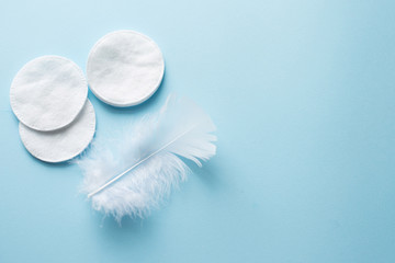 cotton pads with white feather on blue background close up . copy space. top view
