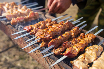 A man fries kebabs on skewers on the grill