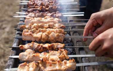 A man fries kebabs on skewers on the grill