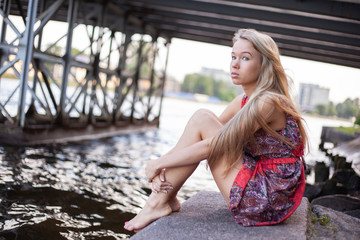 Cute and beautiful blond girl posing for photo in dress at the park