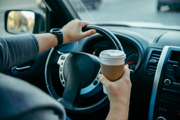 man hands holding steering wheel and cup of coffee. morning booster