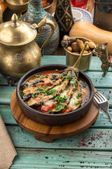 Baked eggplant stuffed with meat, tomatoes, paprika, onion and cheese on blue wooden table