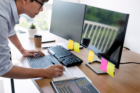 Serious busy hipster young web software developer programmer is coding or programming on a desktop computer information in modern office technologies Website design