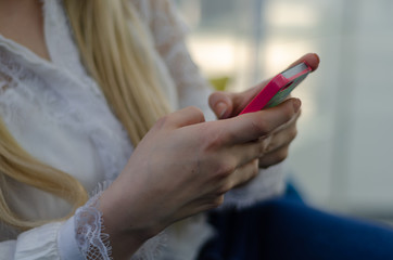 Close up image of young blond woman using her mobile phone background.