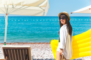 woman with yellow inflatable mattress at seashore. sun loungers.