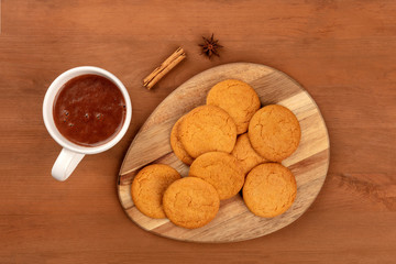 Ginger cookies with a mug of hot chocolate, a cinnamon stick, and an anise star, shot from above on a dark rustic wooden background with copy space
