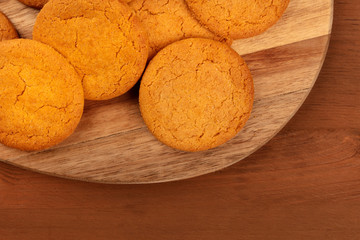 A closeup photo of gingersnaps on a wooden tray, shot from the top on a dark rustic background with a place for text