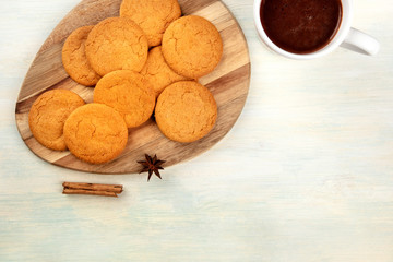 A closeup of ginger snaps, shot from above with a mug of hot chocolate and spices, anise and cinnamon, with copy space