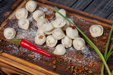 real, delicious, Russian dumplings on the table, with fresh herbs and spices, for cooking design.