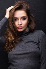 Fototapeta na wymiar Portrait of a beautiful girl in a gray sweater on a black background