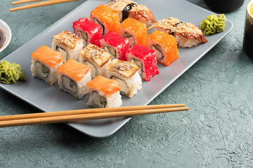 Sushi rolls and sashimi in a grey plate. Traditional Japanese cuisine with salmon, fish, wasabi,...