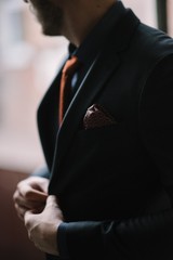 A man with a beard and sunglasses in a gray suit poses on the street to advertise men's clothing. Advertising menswear