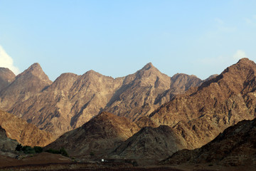 Naklejka na ściany i meble Geological landscape of hatta dam characterised by dry and rocky mountains and lake between scenery mountains, water reservoir Between hills in Dubai, United Arab Emirates