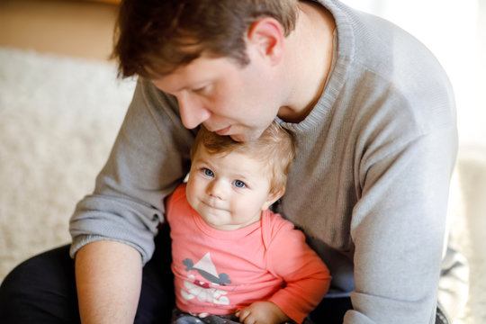 Happy proud young father having fun with baby daughter, family portrait together. Dad with baby girl, love. Man playing with little child at home.