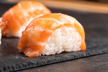 Sushi rolls and sashimi in a black stone plate.