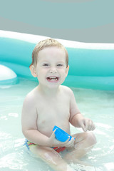 Happy beautiful little boy bathes in pool