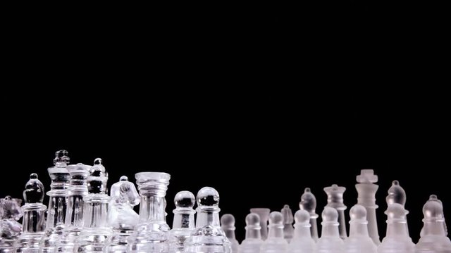 A splendid chessboard with two different full sets of chess pieces (glass material), rotating into a starting position: the choice of the side to take has been made.