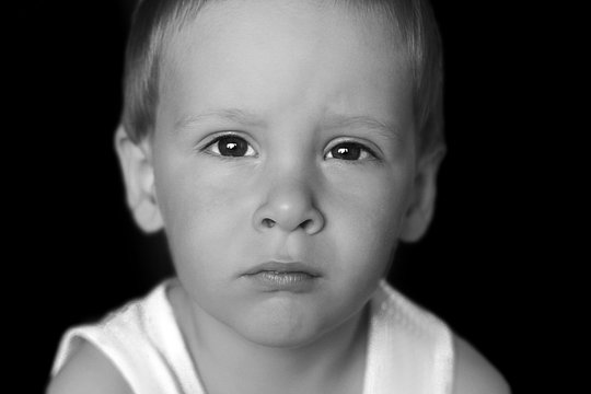 Dramatic portrait of kid looking at camera with angry face, Emotional photo of Displeased boy with unhappy face, Head shot of anger young caucasian boy, Spoiled child and Family violence concept