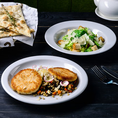 dinner set lunch in a cafe, meat and caesar salad on black table