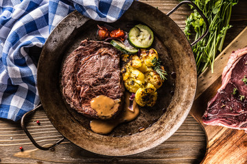 Juicy beef Rib Eye steak roasted potatoes with sauce grilled vegetable salt pepper and herbs in...
